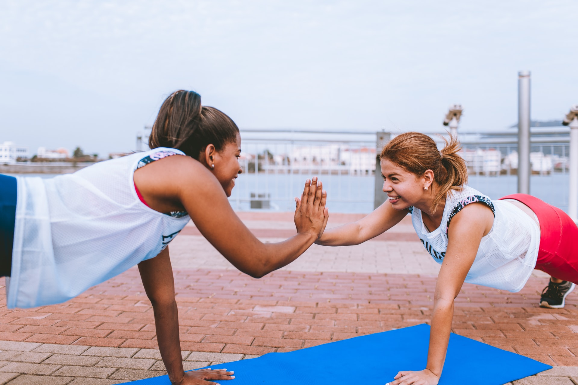 Two women high fiving while doing a press up